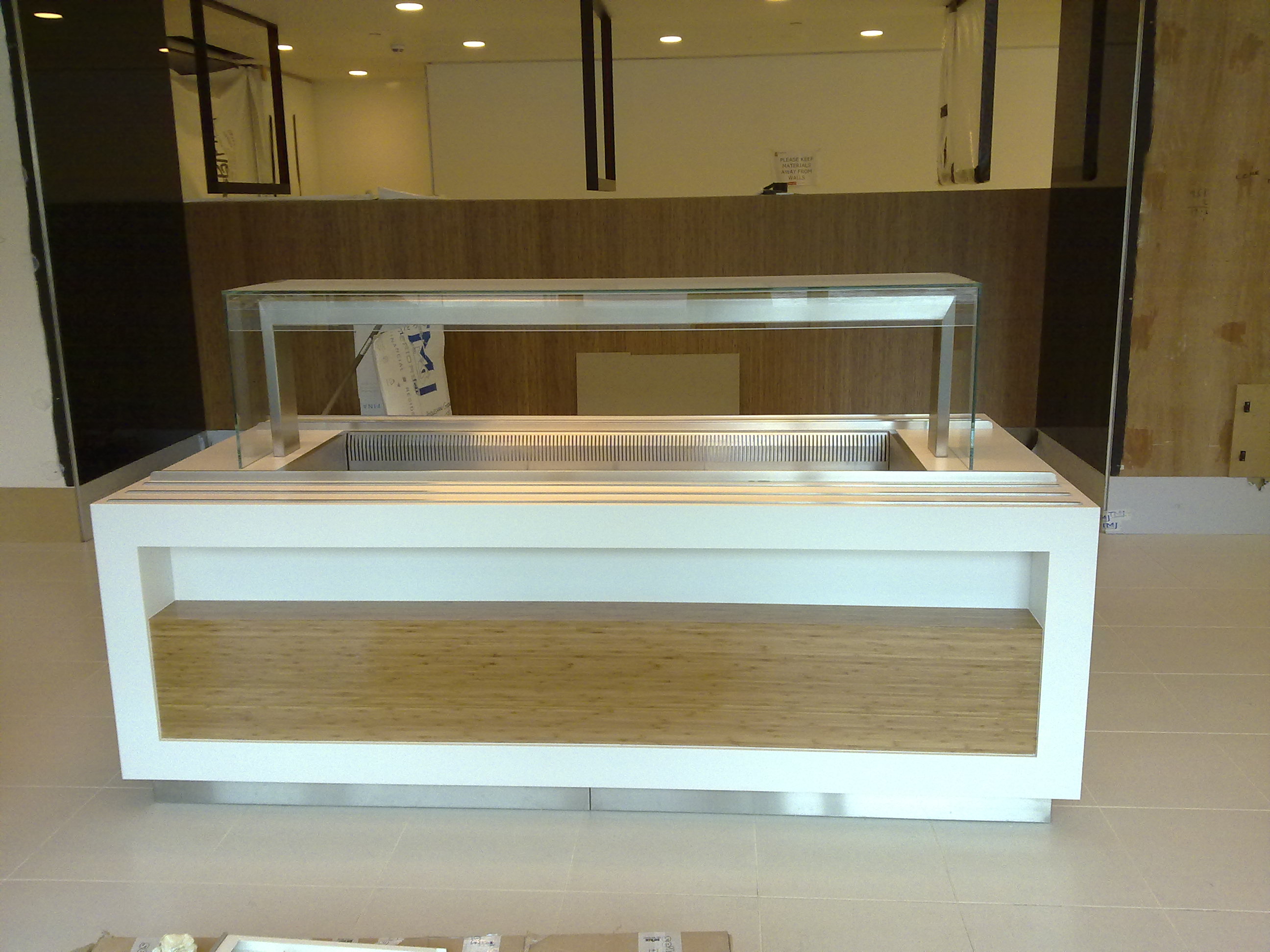 (Addleshaw) Law firm  – London  Glacier white corian and stainless steel tray runners throughout with bamboo veneer impulse displays 